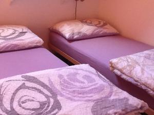 Tartegnin拉托里尔住宿加早餐旅馆的带紫色床单的客房内的三张床