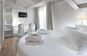 里米尼里米尼套房酒店的一间白色卧室,配有一张床和两把椅子