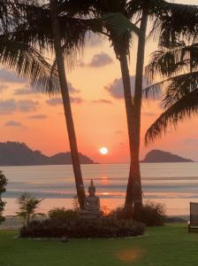 象岛Vitamin sea villas Koh Chang的日落时分,佛像坐在两棵棕榈树下