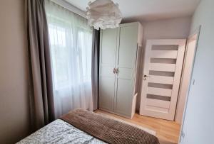 格但斯克Apartament Młody Gdańsk - bezpłatny parking, mocne WiFi, dobre połączenie z lotniskiem的一间卧室配有一张床、一个衣柜和一个吊灯。