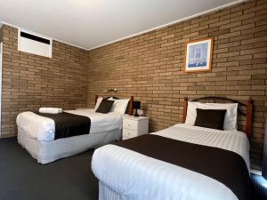 沃东加Warrina Motor Inn Wodonga CBD的一间卧室设有两张床和砖墙