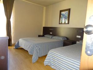 安道尔城卡尔福纳尔旅馆的酒店客房,配有两张带条纹床单的床