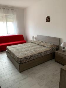 圣巴特罗摩艾美尔Appartamento SanBart Mare的一间卧室配有一张床和一张红色的沙发
