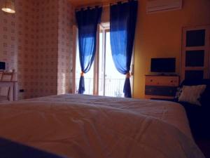 萨莱诺Leucosia Bed & Breakfast的一间卧室配有一张带蓝色窗帘的床和一扇窗户