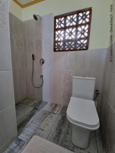 迪亚尼海滩Gästehaus Diani的一间带白色卫生间的浴室和窗户。