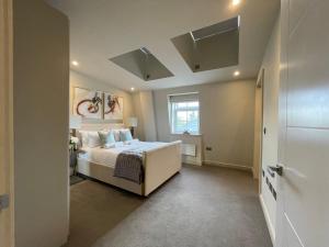 齐格威尔luxurious, 2 bed, 2 bath penthouse apartment in highly desirable Chigwell CHCL F8的卧室配有白色的床和窗户。