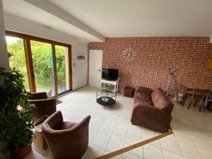 圣库隆Maison de vacances l’Émeraude的客厅配有沙发、椅子和电视