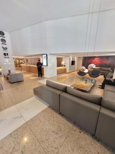 巴西利亚Lets Idea Brasília Hotel By Rei dos Flats的站在大厅里的人,有一张沙发和椅子