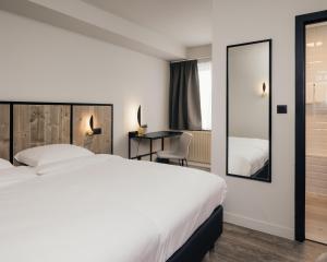 莱斯河畔的汉恩Hotel Au lit des ours的酒店客房带一张床、一张书桌和一面镜子