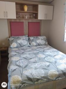 斯凯格内斯Deluxe 3 Bedroom Caravan with extra en-suite North Shore的一张带蓝色和白色棉被和枕头的床