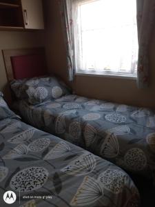 斯凯格内斯Deluxe 3 Bedroom Caravan with extra en-suite North Shore的卧室设有两张单人床和窗户。