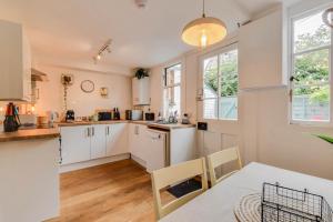 赛伦塞斯特Cheerful 3 bed Grade II Central Cottage的厨房配有白色橱柜和桌椅