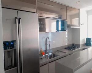 里约热内卢Apartamento luxuoso com infra completa próximo a Praia da Barra da Tijuca的厨房配有白色橱柜和不锈钢冰箱