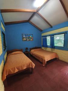 Santa CruzEl Encanto Garden Hotel的蓝色墙壁客房的两张床
