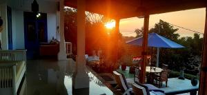 罗威那Cantik Villa的太阳落在房子里,配有桌子和遮阳伞
