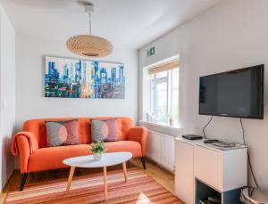 雷克雅未克塞姆公寓式酒店的客厅配有橙色沙发和电视