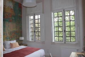圣地亚哥玛迪尔达斯精品酒店的一间卧室设有一张床和三个窗户。
