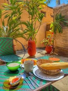 科托努La Guesthouse Étoile的一张桌子,上面放着一盘食物和一碗面包