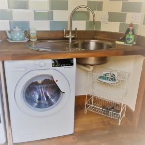 汤顿Meg's Cottage的厨房配有水槽和洗衣机