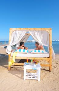 赫尔格达Pickalbatros Blu Spa Resort - Adults Friendly 16 Years Plus- Ultra All-Inclusive的三人躺在沙滩上的床上