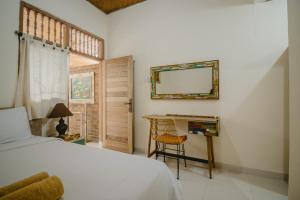 登巴萨萨姆布鲁恩马斯民宿的一间卧室配有一张床、一张书桌和一面镜子