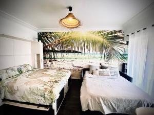 卢贝新城Baie-Des-Anges Studio Front de Mer的一间卧室设有两张床和棕榈树壁画