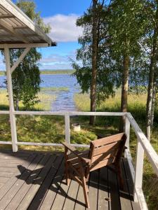 BurträskSvens Stuga的木制长椅,位于俯瞰湖泊的甲板上