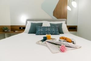 亚历山德鲁波利斯Magico Suites City Heart Luxury Appartments的一张带两条毛巾的床和一盘食物