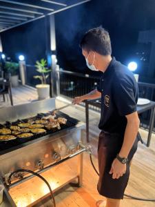 爱妮岛S Resort El Nido的一个人在烧烤架上做饭
