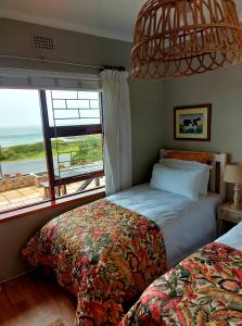 克莱因蒙德La Mer Seafront Selfcatering Accommodation Kleinmond的一间卧室设有两张床和大窗户
