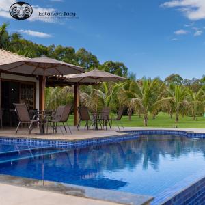 戈亚斯州上帕莱索Estancia Jacy的毗邻度假酒店的带椅子和遮阳伞的游泳池