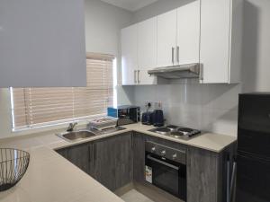 哈博罗内Sarona city Habitat Alpha apartments C202 Gaborone的厨房配有白色橱柜和炉灶烤箱。