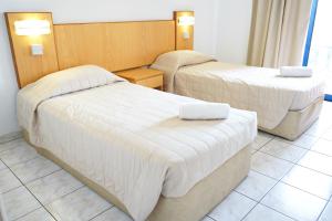 阿依纳帕Green Bungalows Hotel Apartments的配有白色床单的酒店客房内的两张床
