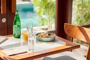 龙目岛库塔KU Villas的一张桌子,上面放着一碗食物和一瓶啤酒