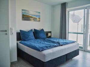 比苏姆Ferienbude an den Wehlen的一间卧室配有一张带蓝色床单的床和一扇窗户。