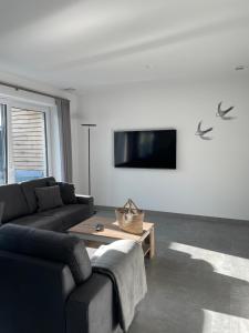 比苏姆Ferienbude an den Wehlen的客厅配有沙发和墙上的电视
