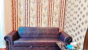 拉合尔Hotel Super Seven的一张棕色皮沙发,坐在一个玻璃桌的房间