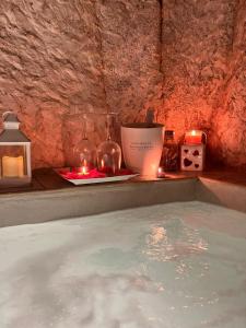 奥斯图尼Tama67 suite的客房内的热水浴池配有蜡烛和蜡烛
