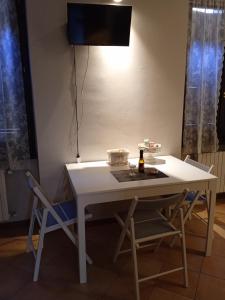 克雷莫纳La strada del liutaio nel cuore di Cremona的一张带两把椅子的白色桌子和墙上的电视