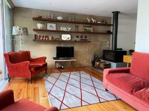 里斯本Casa das Boganvilias - Moradia com jardim的客厅配有2张红色沙发和电视