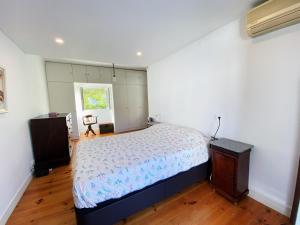 里斯本Casa das Boganvilias - Moradia com jardim的一间卧室配有一张床,铺有木地板