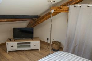 Tournan-en-BrieCROIX BLANCHE - LE LOGIS的一间卧室配有一张床,并在橱柜上配有电视