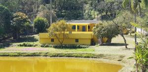 苏扎努Bela Chácara的坐在水体旁边的黄色房子