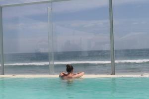 曼克拉Hotel Del Mar Mancora的坐在游泳池里看着大海的女人