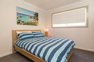 史密斯湖Happy Daze的卧室配有蓝色和白色条纹床和窗户。