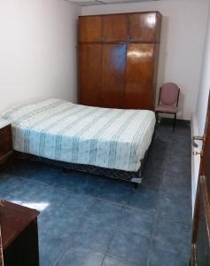 萨尔塔SUMAQ WASICHA SALTA的一间卧室配有一张床、一个木制橱柜和一把椅子
