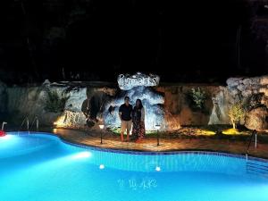 ChegātPugmarks Jungle Lodge的有一对夫妇在晚上站在游泳池前