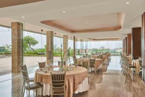 泗水泗水瓦萨酒店的用餐室配有桌椅和大窗户