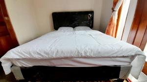 迪昂Homestay Merpati Dieng Syariah RedPartner的卧室内一张带白色床单和黑色床头板的床