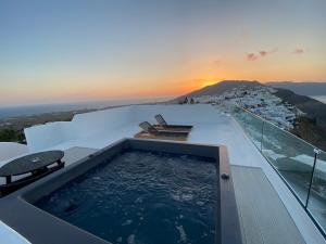 伊亚ArmonOia Suites的屋顶上的热水浴池,享有日落美景